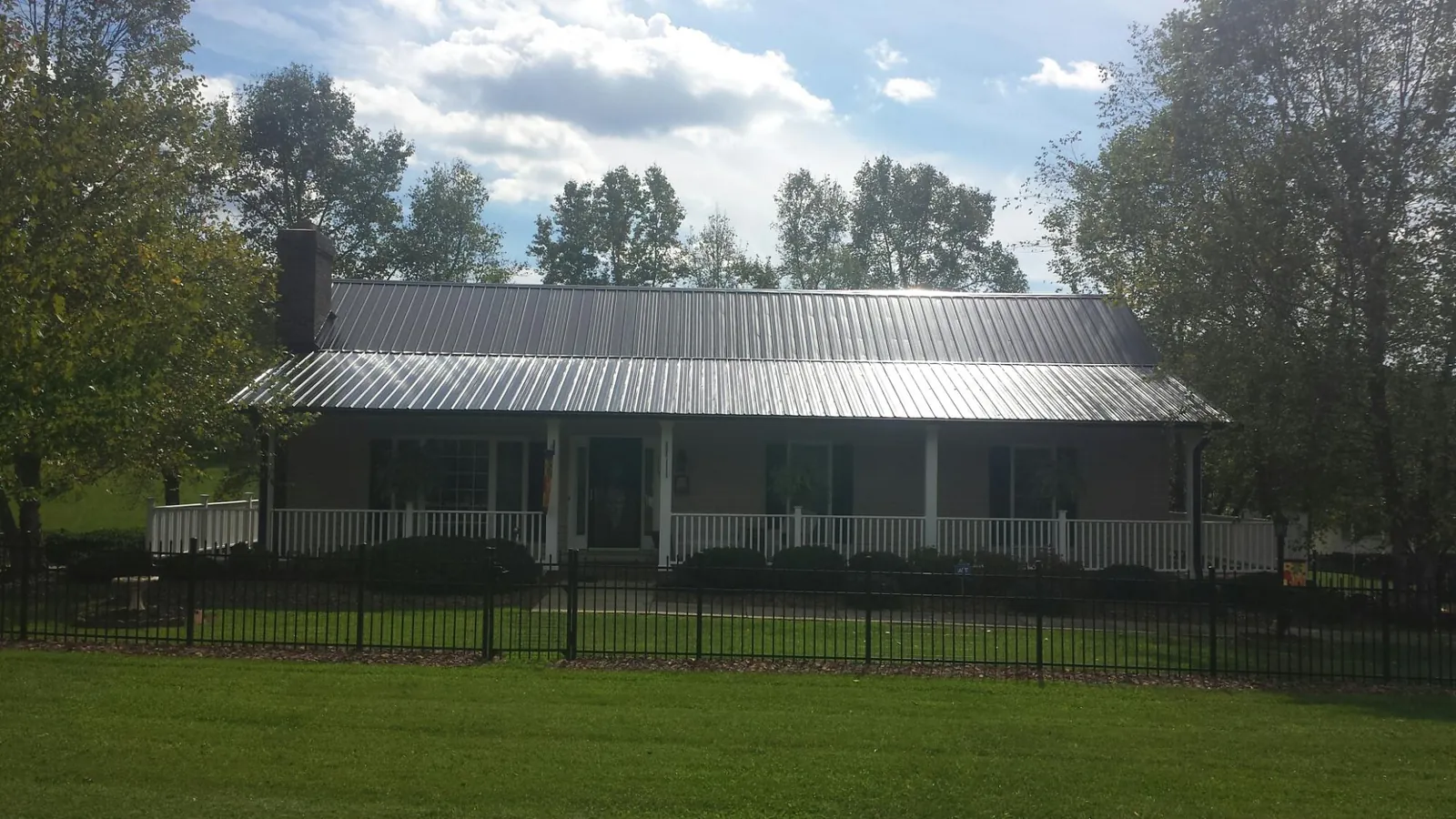Gray metal roof on a brick ranch with a full width front porch — Gutter Guard Installation work by our crew in Forest Lakes