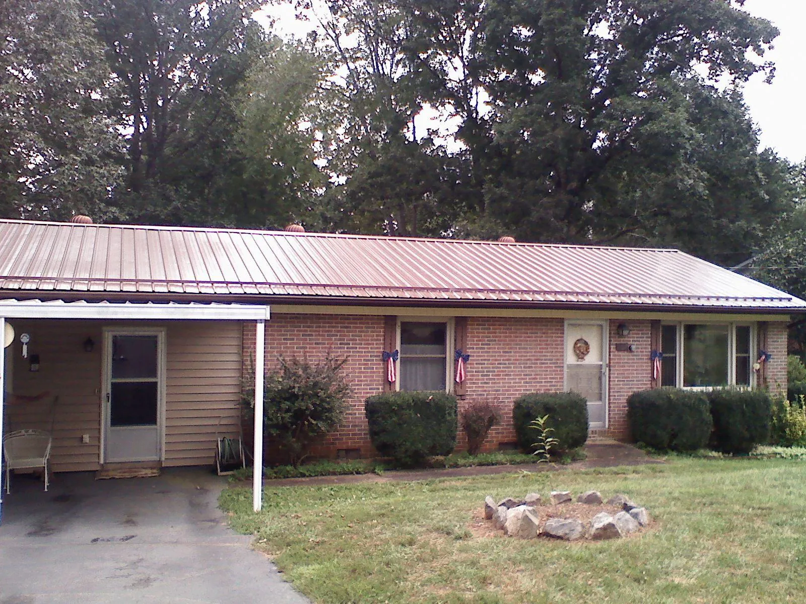 Bronze metal roof and carport on a brick ranch home — Roof Repair work by our crew in Forest Lakes