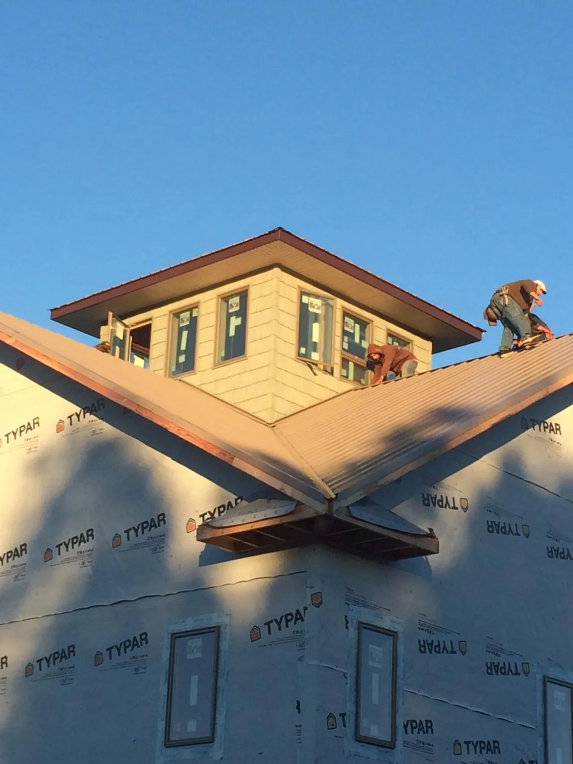 Roofers working around a rooftop cupola on a new metal roof at sunset — Roof Waterproofing in Forest Lakes by Roofing Brothers